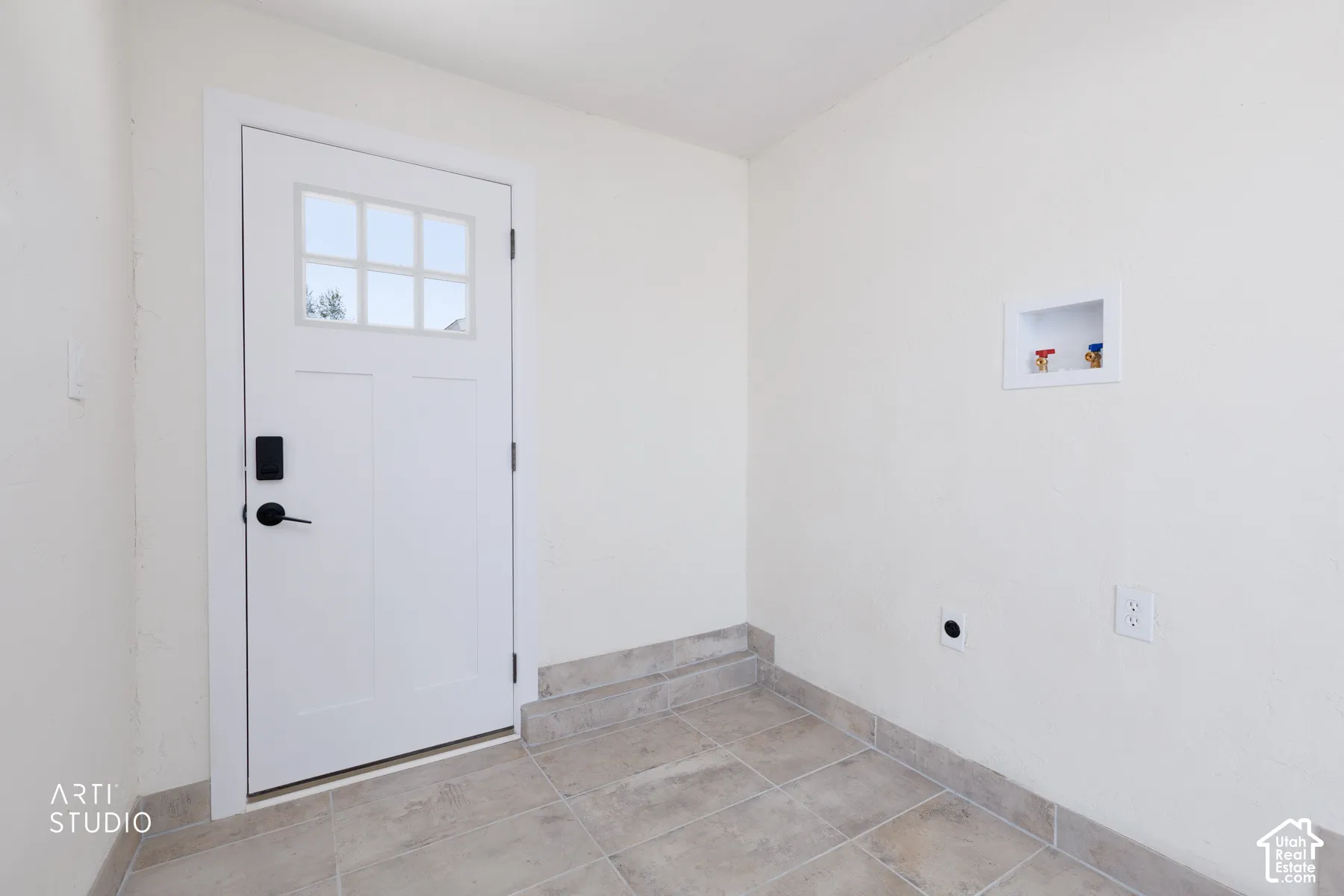 White paneled door with glass inserts, black hardware, and tile flooring