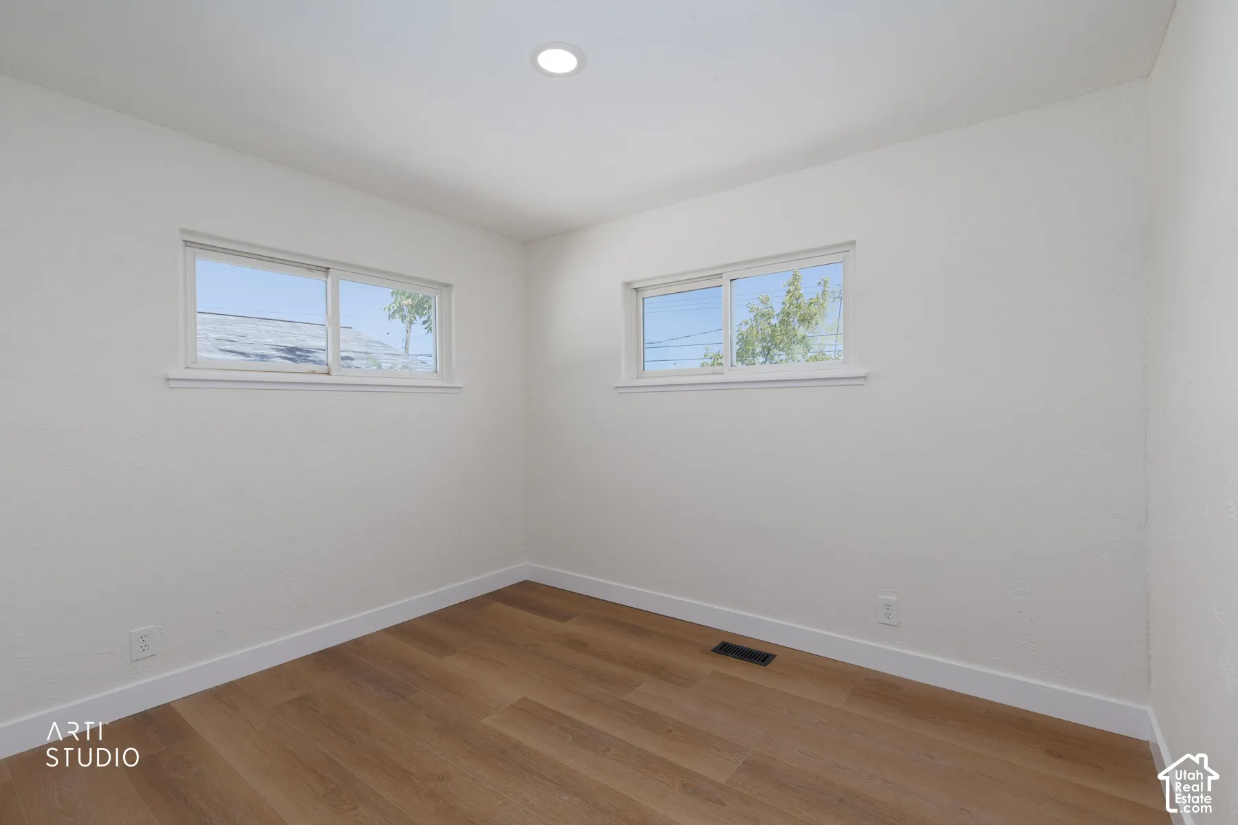 Wood-finish flooring with white baseboards, recessed ceiling lighting, and two sliding windows