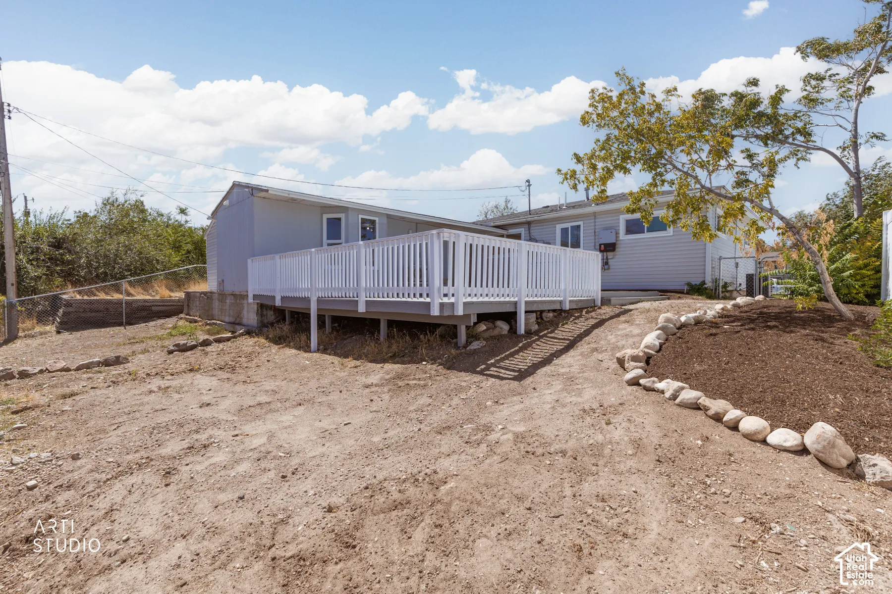 Exterior siding, white deck railing, raised deck, and a landscaped rock border