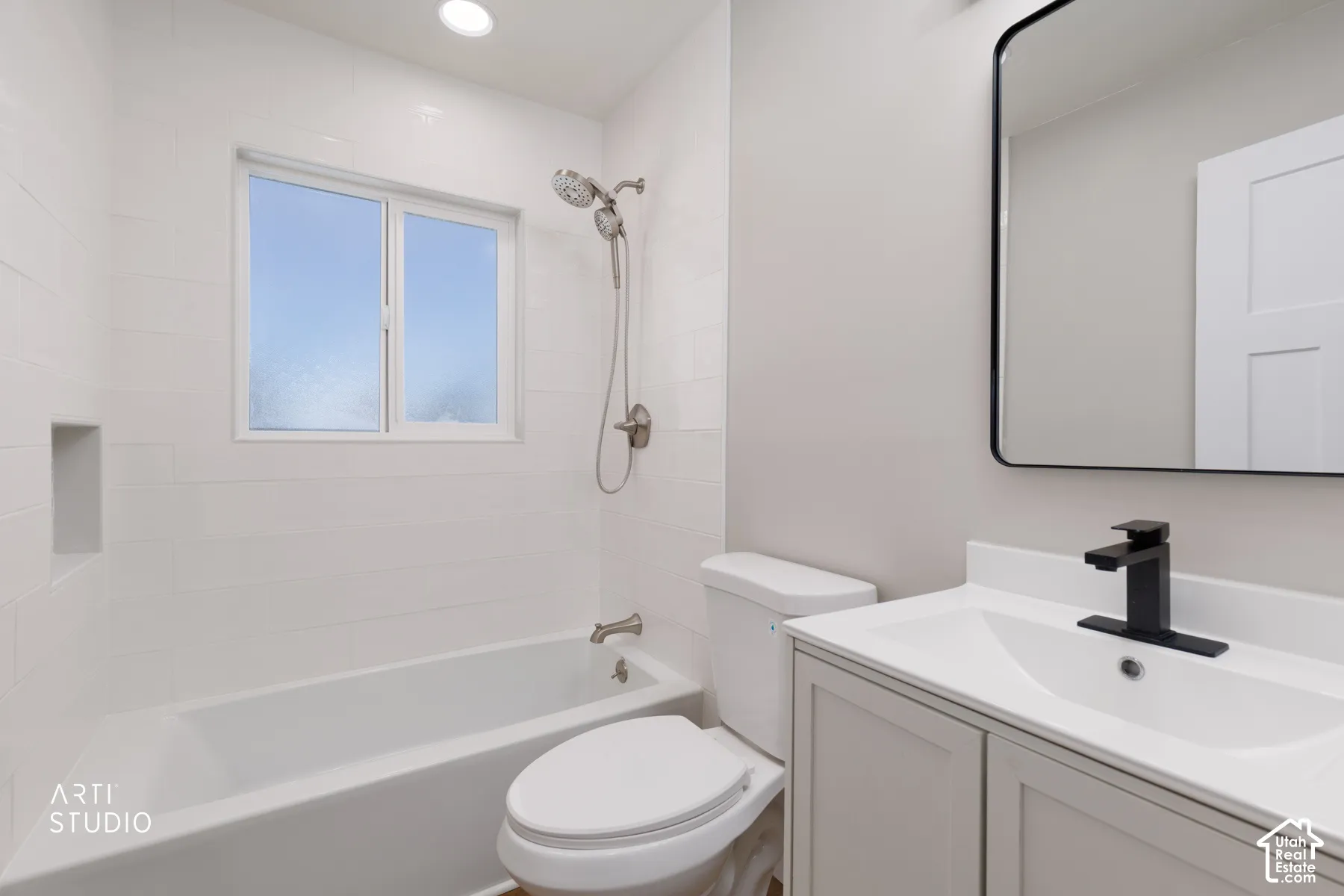 White subway tile surround with integrated niche, modern vanity with white countertop, black-framed mirror, and black matte faucet