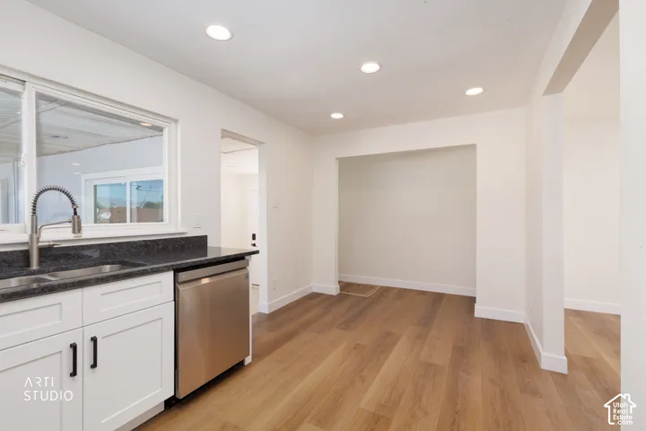 Kitchenette featuring recessed lighting, a stainless steel sink, a stainless steel dishwasher, white cabinetry with dark hardware, and wood-finish flooring