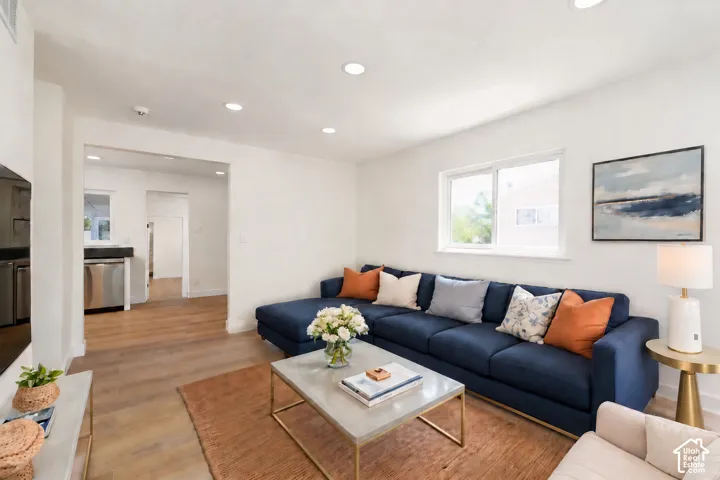 Recessed lighting, wood-finish flooring, white walls, and a large window with white trim