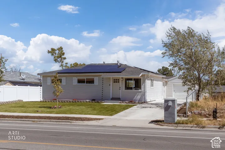 Single-story exterior featuring solar panels, light-toned siding, a white front door with panel detailing, a detached garage with a white door, and a white privacy fence