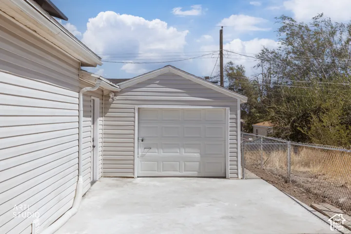Attached garage with a white panel door and concrete driveway