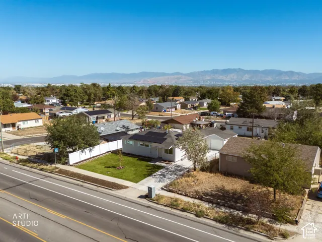 Manicured front lawn, white privacy fence, solar panels, paved driveway, surrounding neighborhood