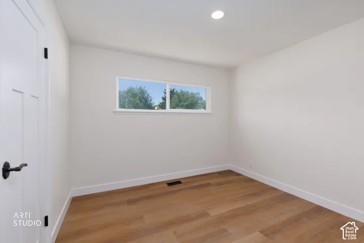 Recessed ceiling lighting, wood-finish flooring, white trim, white wall finishes, and a multi-pane window