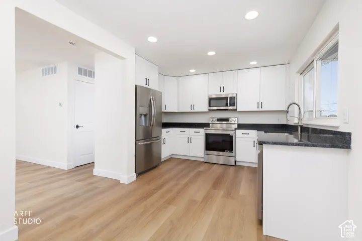 Modern kitchen with white cabinetry and dark countertops