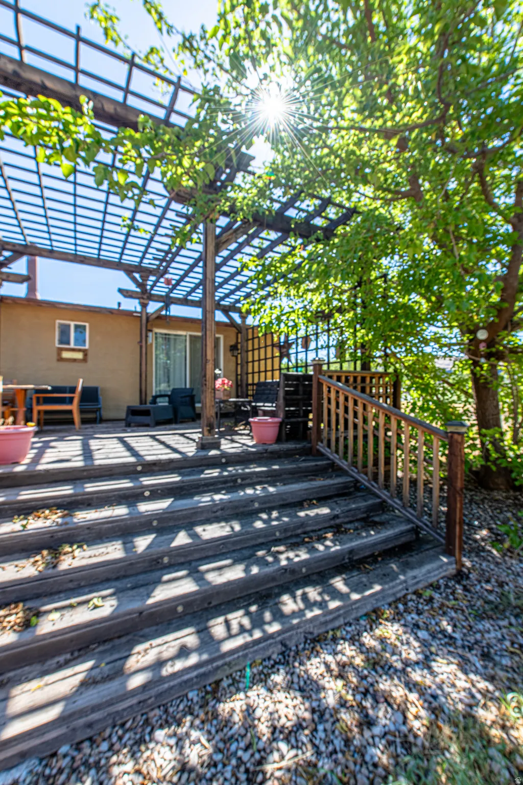Expansive wood deck with a pergola, exterior sliding glass door, wood railing, and integrated deck lighting