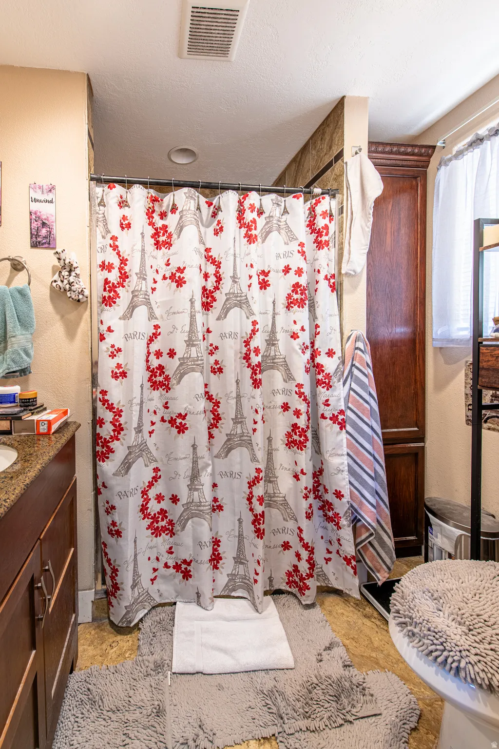 Built-in wood-finish cabinetry, recessed ceiling lighting, and a shower with tiled surround