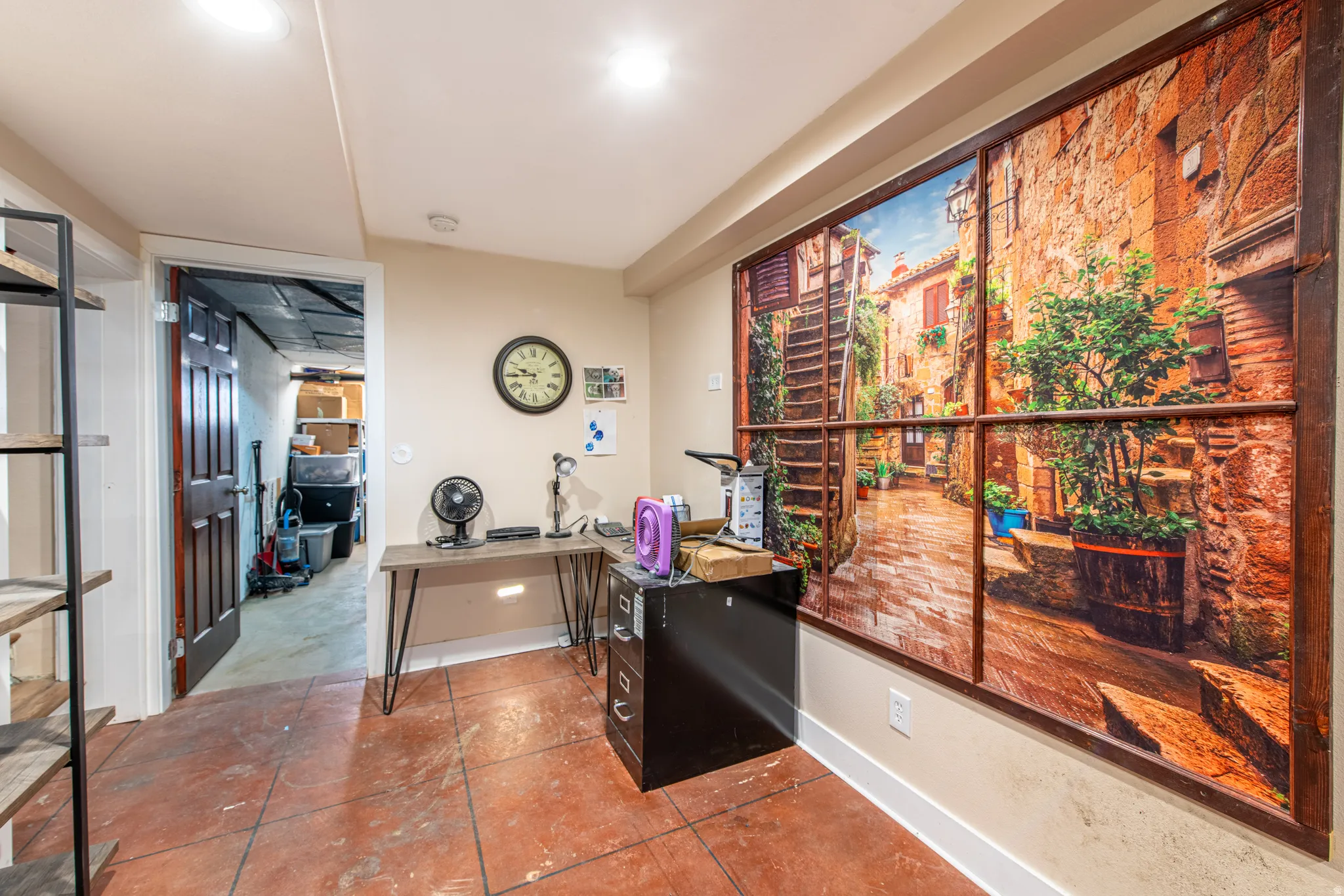 Recessed ceiling lighting, light-toned wall paint, white trim, red-toned tile flooring, and a dark wood-finish door
