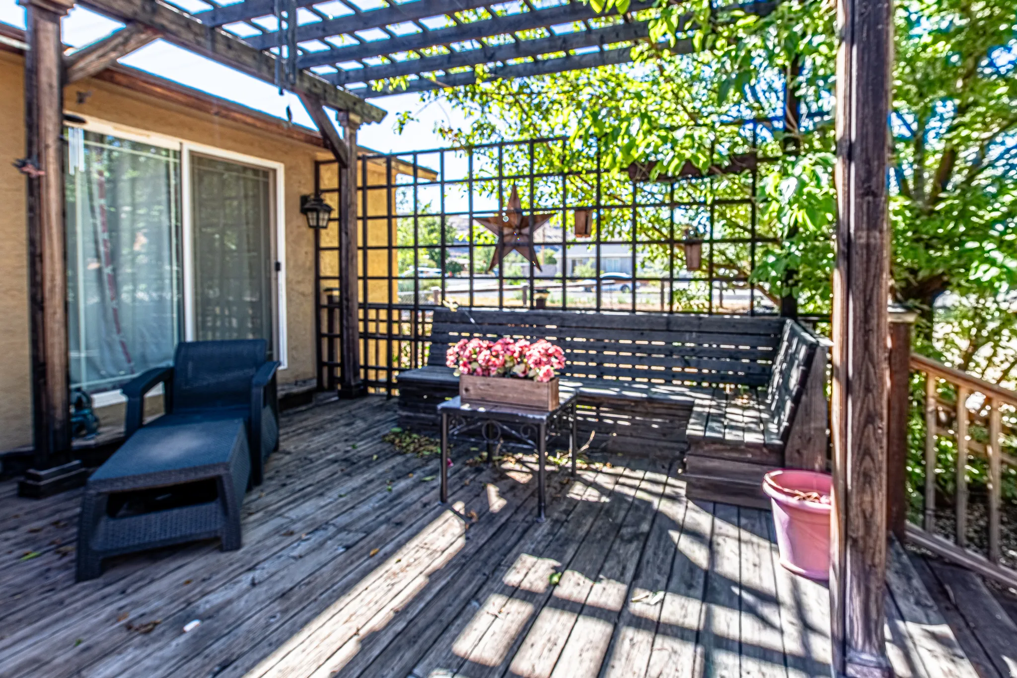 Wood-plank deck with a pergola, lattice panels, and a sliding glass door