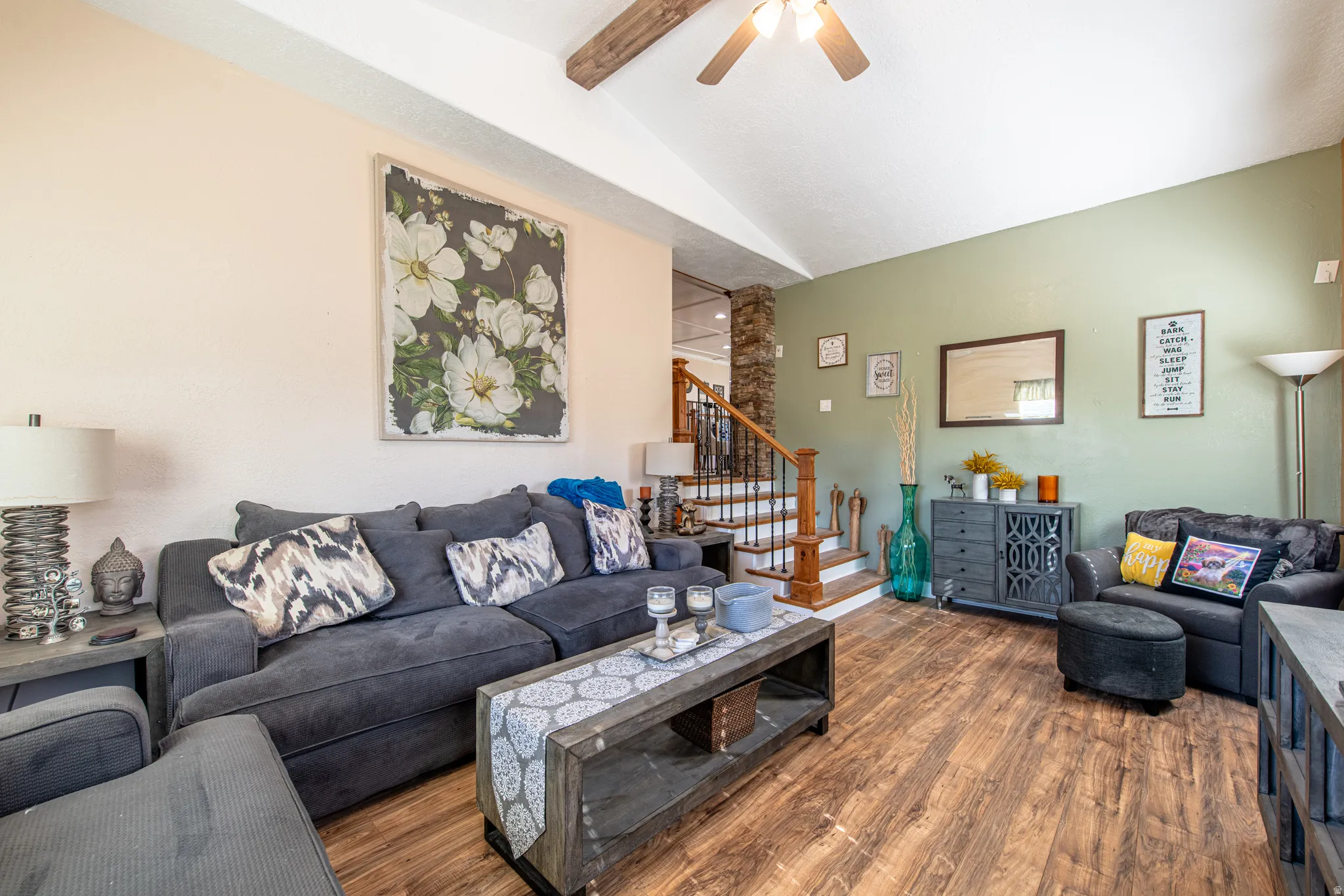 Vaulted ceiling with wood beam accents, wood-finish flooring, and a ceiling fan