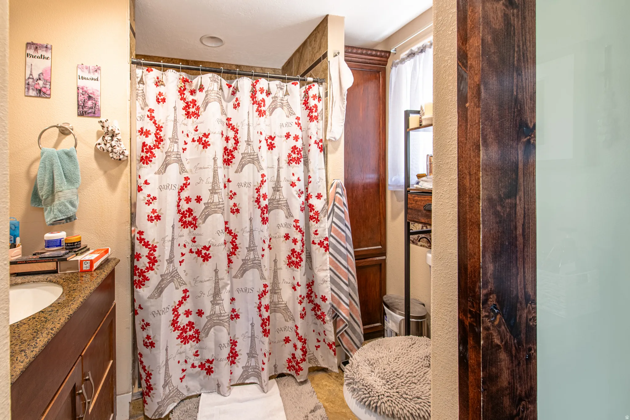 Vanity with integrated sink and stone-finish countertop, wood-finish cabinetry, and built-in wood-finish storage