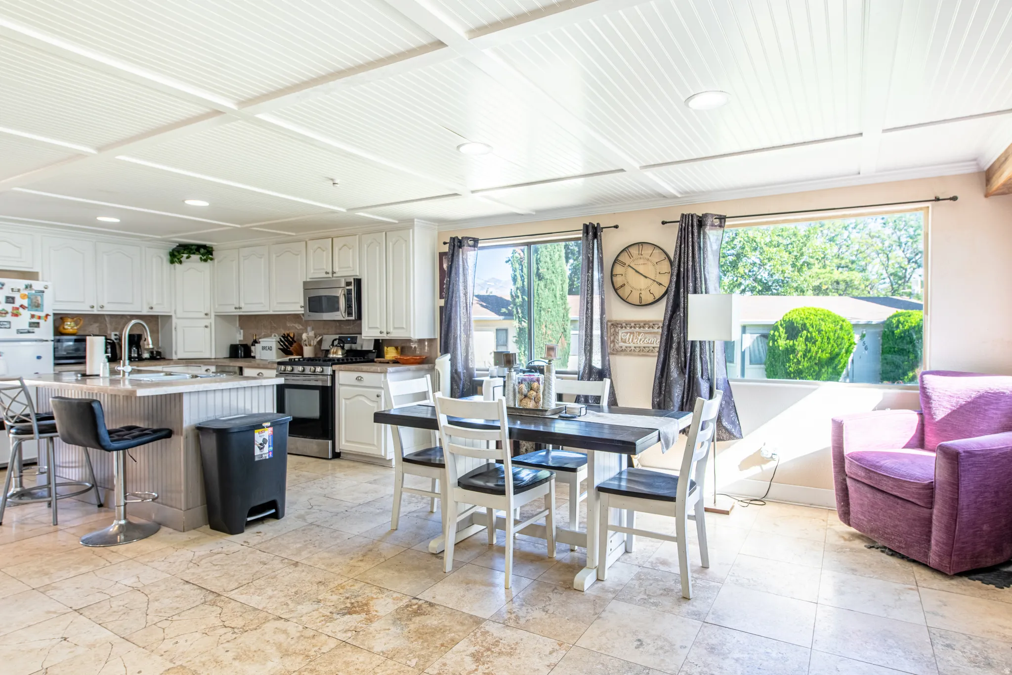 Recessed lighting, wood-paneled ceiling, white cabinetry, integrated stainless steel appliances, and tile flooring