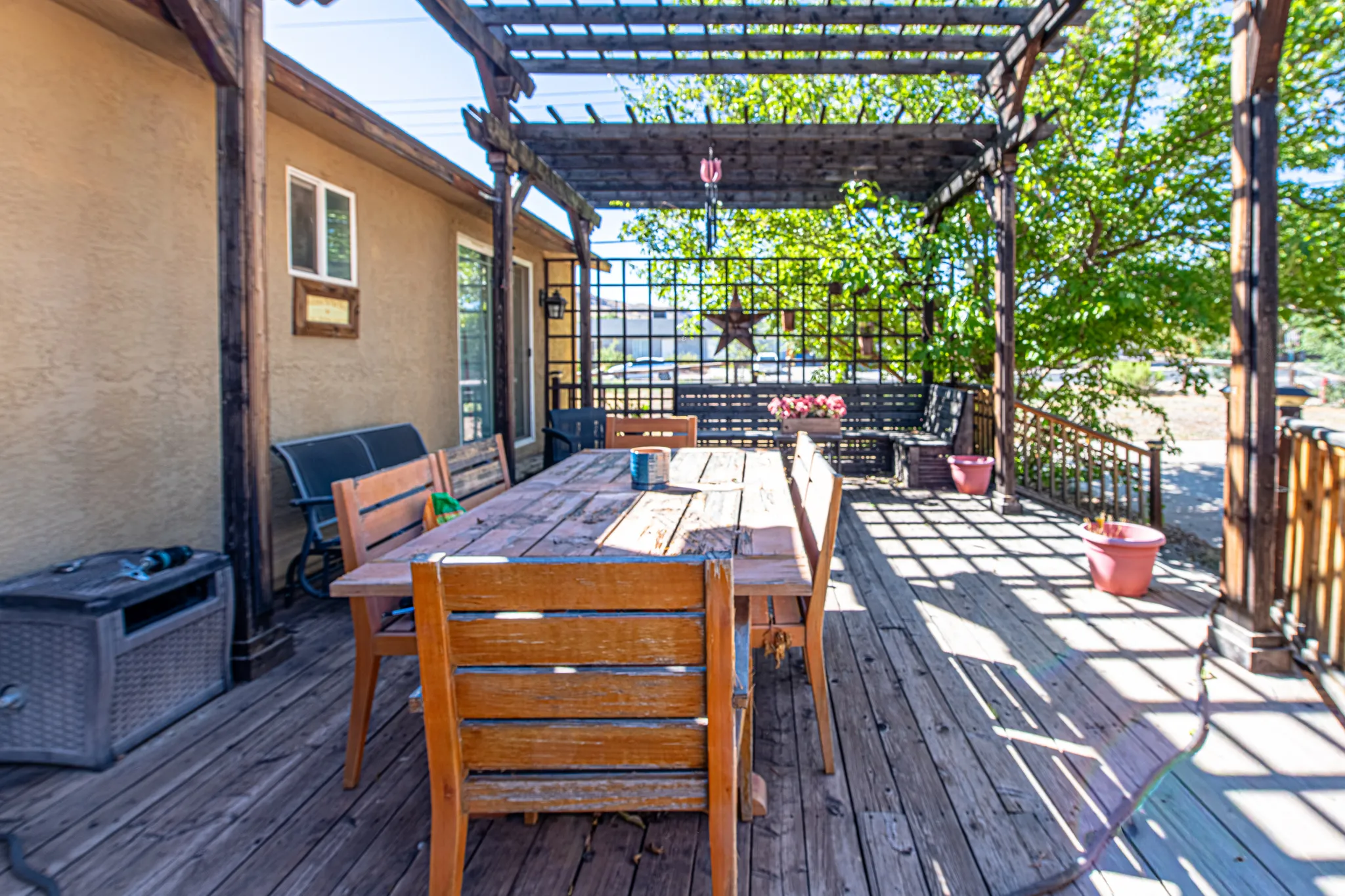 Expansive wooden deck featuring a pergola, stucco exterior, and a lattice privacy screen