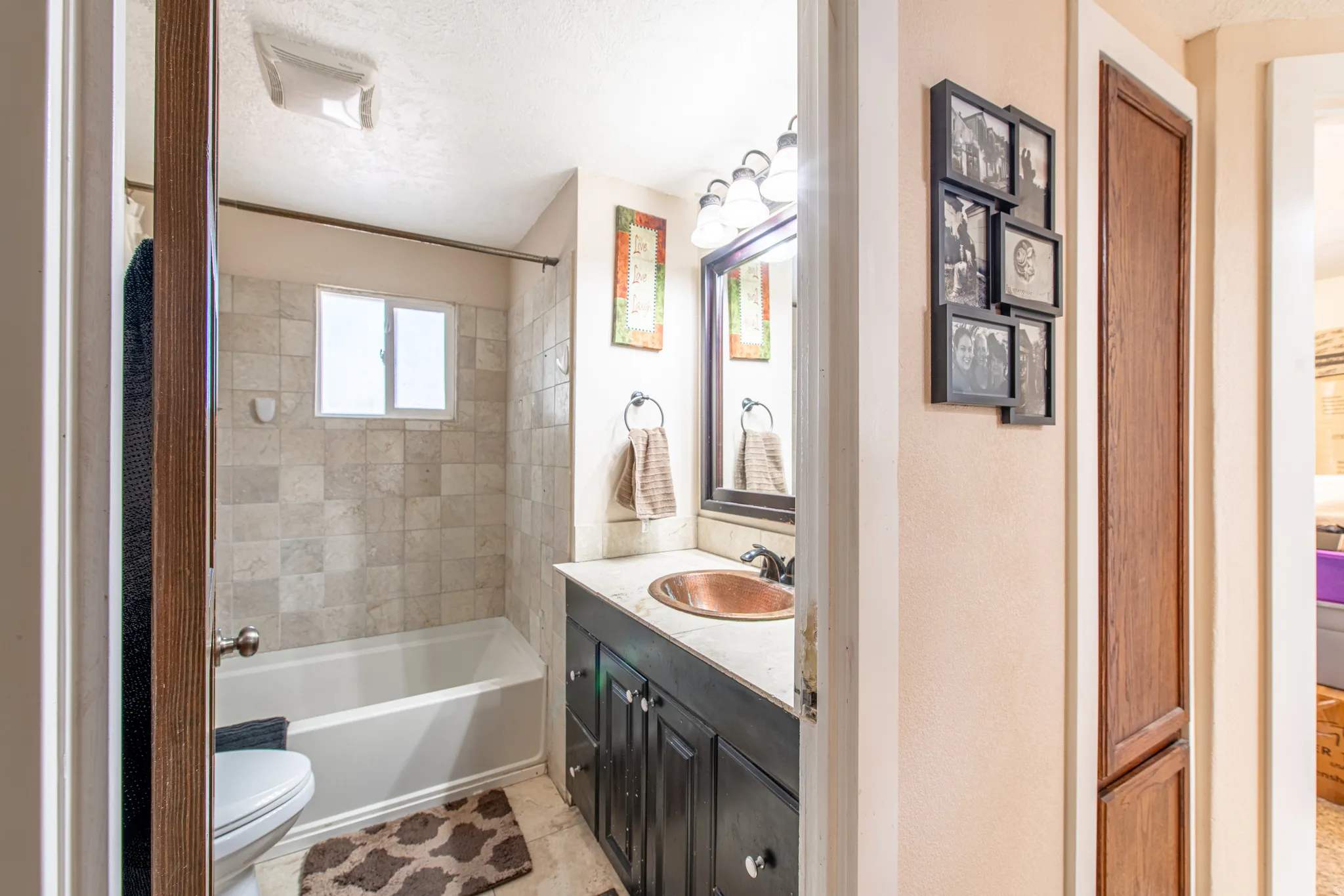 Bathroom featuring a single vanity with a copper-finish sink, dark wood cabinetry, and a tile shower surround