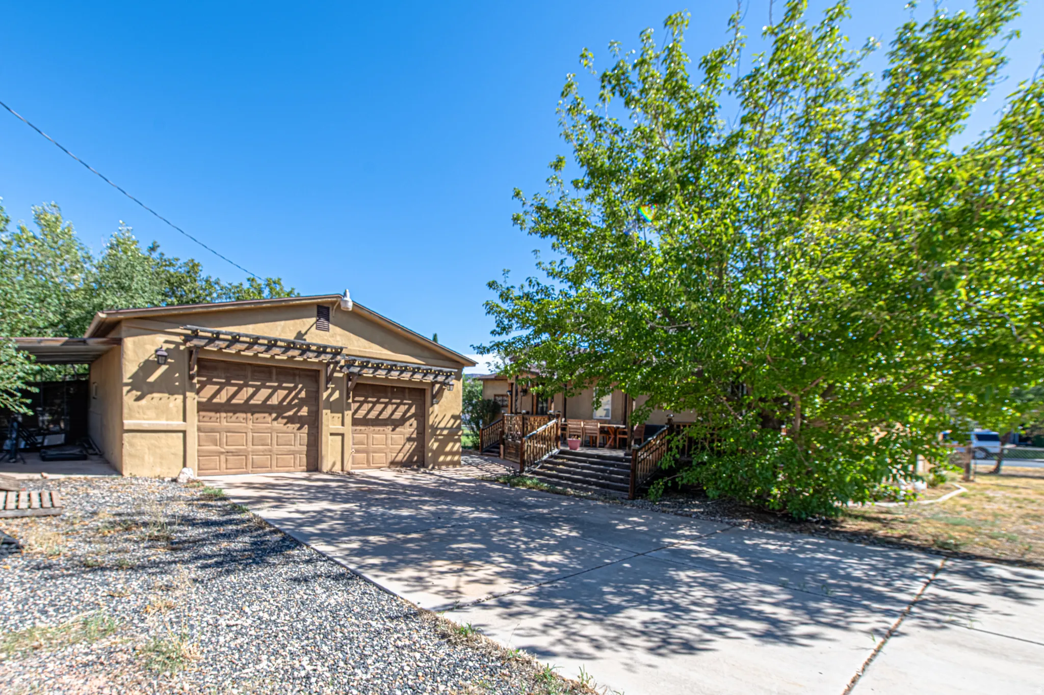 Stucco exterior with a two-car garage featuring wood-finish doors and decorative pergolas