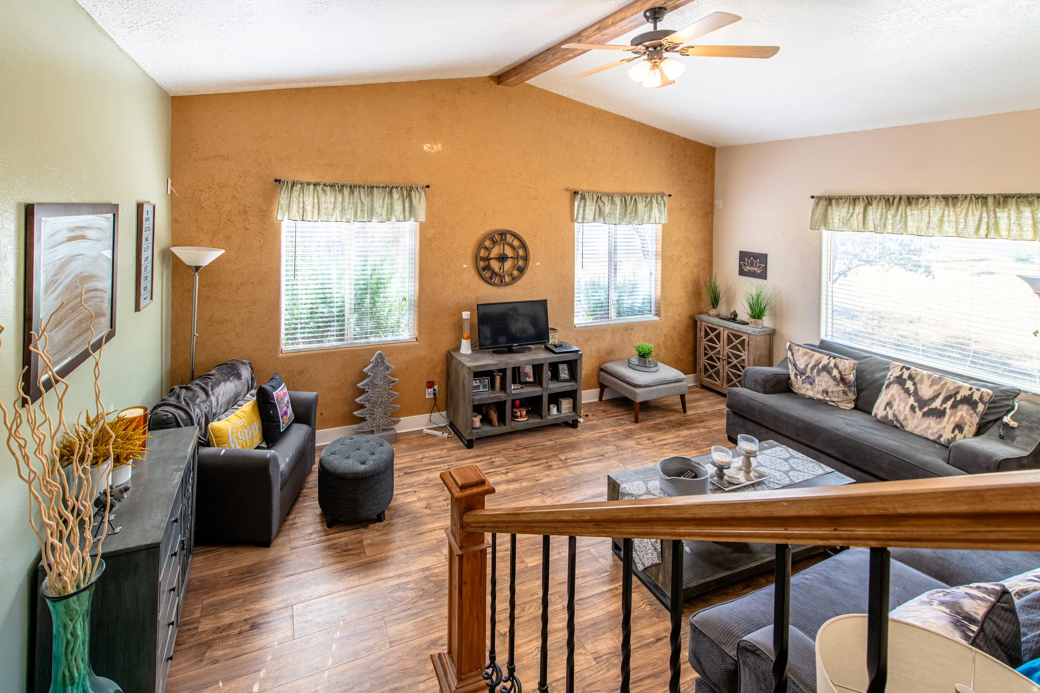 Vaulted ceiling, exposed wood beam, ceiling fan, wood-finish flooring, multiple windows