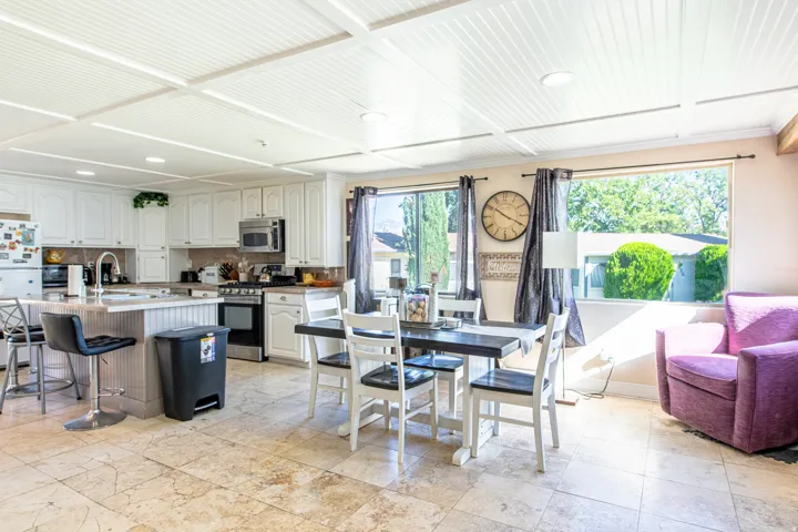 Recessed lighting, wood-paneled ceiling, white cabinetry, integrated stainless steel appliances, and tile flooring