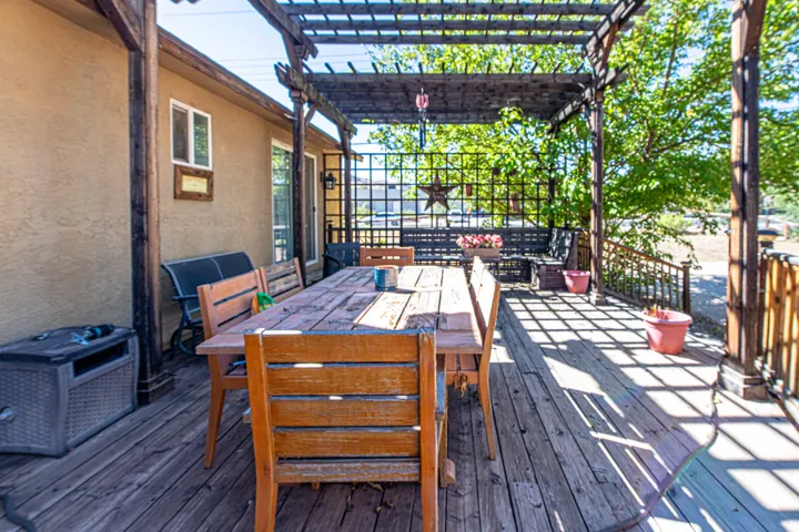 Expansive wooden deck featuring a pergola, stucco exterior, and a lattice privacy screen