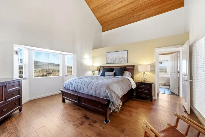 Vaulted wood-paneled ceiling, wood-finish flooring, bay window, light yellow wall accents, and an open doorway