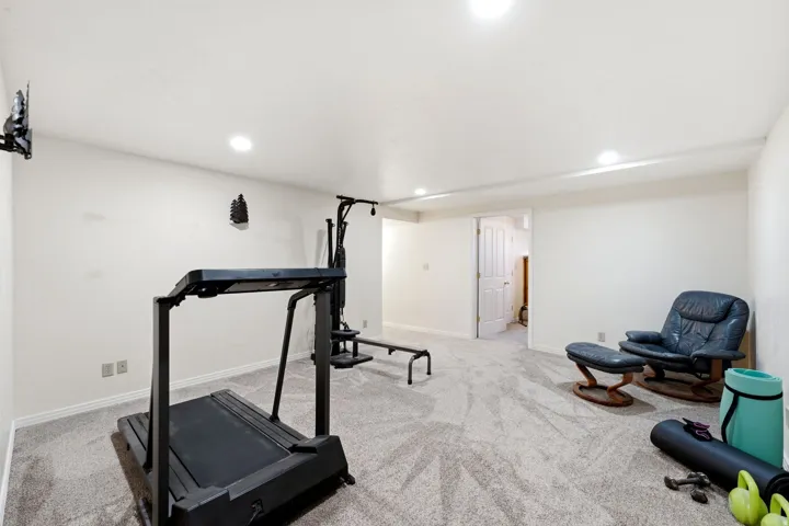 Recessed lighting illuminates a spacious room featuring wall-to-wall carpeting and neutral wall finishes