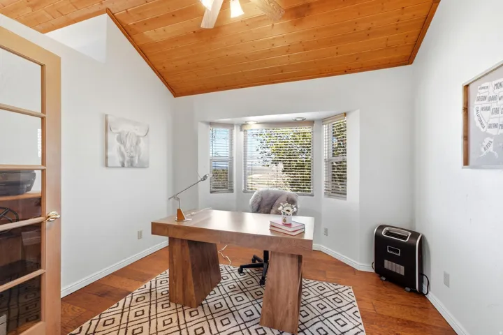 Vaulted wood-paneled ceiling with a ceiling fan, bay window with blinds, wood-finish flooring, and French doors