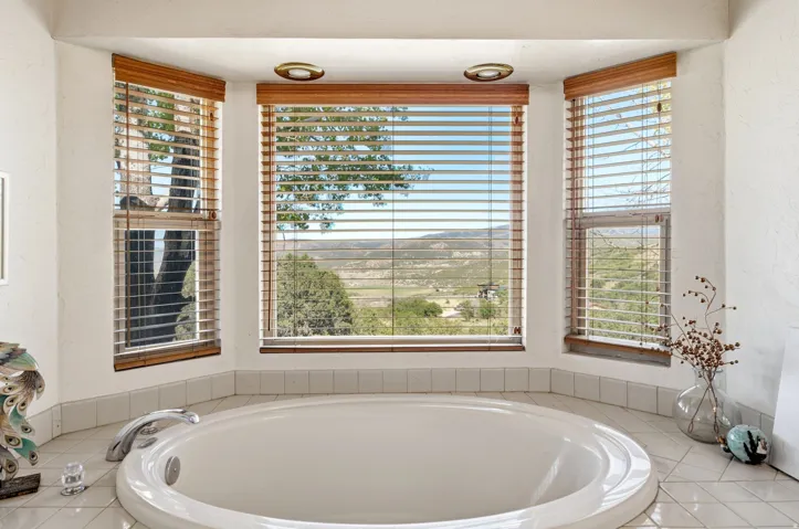 Built-in soaking tub with a curved surround, chrome fixtures, and a tiled floor