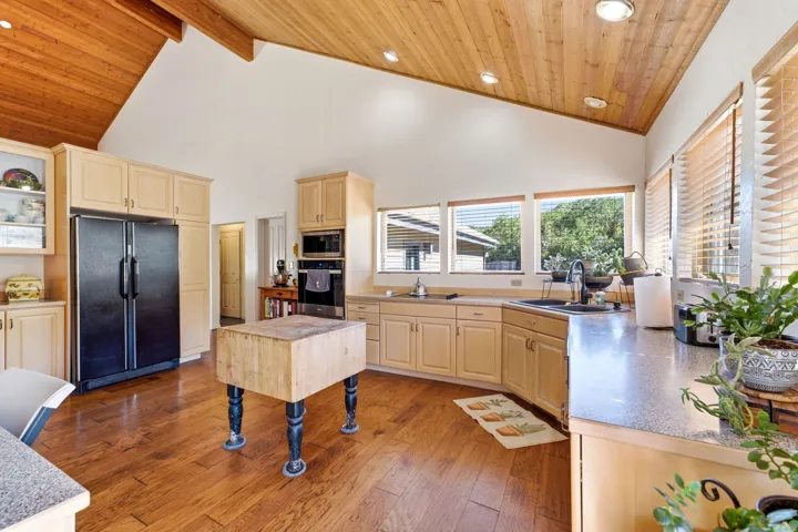Vaulted wood-paneled ceiling, recessed lighting, wood-finish flooring, ample cabinetry, and built-in appliances
