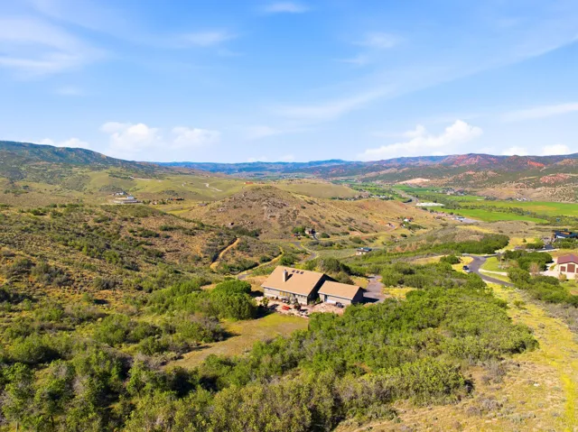 Expansive property with a multi-level structure featuring a stone exterior and a pitched roof, surrounded by natural terrain and distant mountains