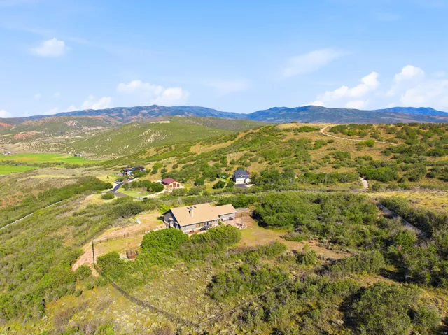 Expansive property with a single-story residence, surrounded by natural landscaping and distant mountains
