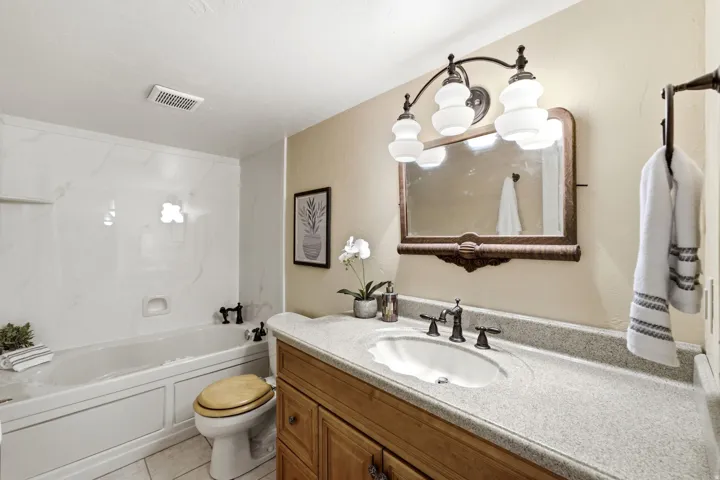 White bathtub with built-in paneling, black fixtures, and a white tiled floor