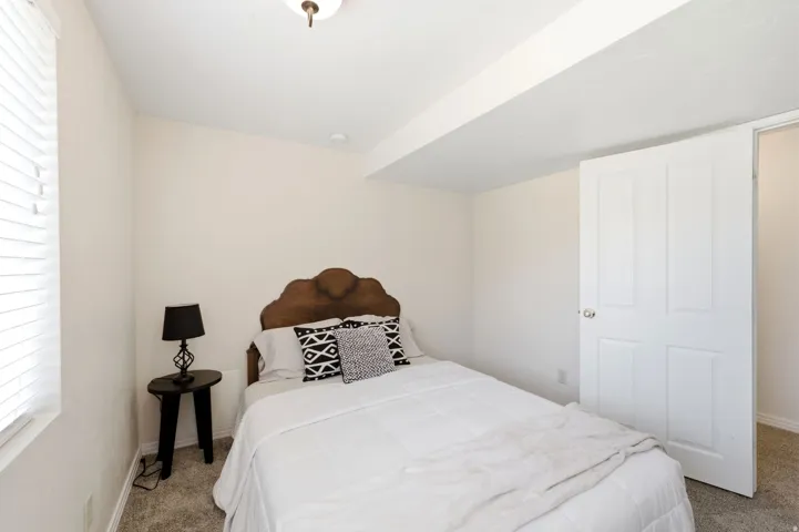 Neutral wall paint, textured carpeting, and white window blinds