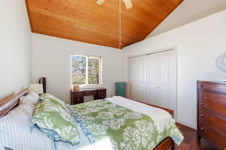 Vaulted wood-paneled ceiling, ceiling fan, wood-finish flooring, built-in bi-fold closet doors, and single window with blinds