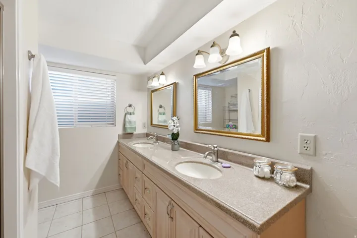 Double vanity with integrated sinks, stone-finish countertop, wood cabinetry, and dual framed mirrors