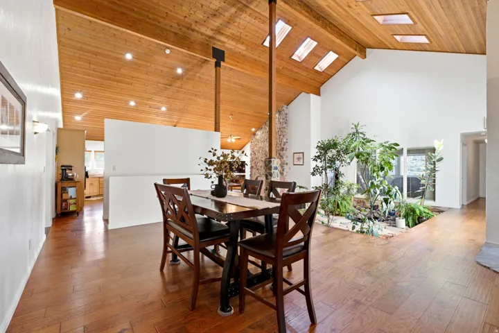 Vaulted wood-paneled ceiling with skylights, wood-finish flooring, and an interior garden feature
