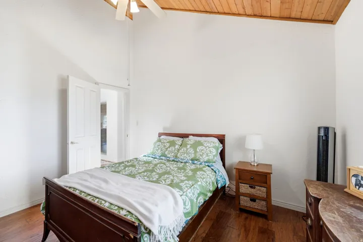 Vaulted wood-paneled ceiling with a ceiling fan, hardwood flooring, and white walls