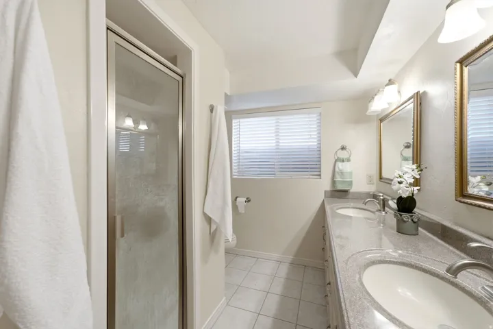 Bathroom featuring dual vanity with undermount sinks, stone-finish countertop, and framed mirrors