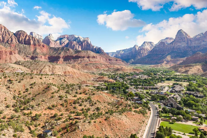 Mountainous terrain with natural rock formations, a developed community, and a winding paved road