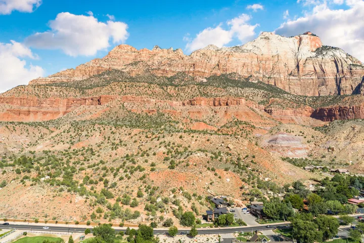 Mountainous terrain with varied rock formations, sparse green vegetation, and a winding road below