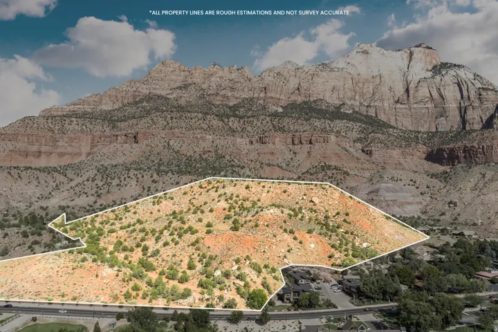 Expansive undeveloped land featuring natural desert vegetation, a mountainous backdrop, and proximity to a developed residential area