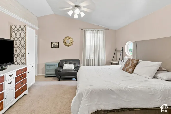 Vaulted ceiling with a ceiling fan, window with curtain, plush carpeting, and built-in cabinetry