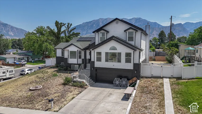 Two-story residence with a two-tone exterior, a concrete driveway, and a white fence