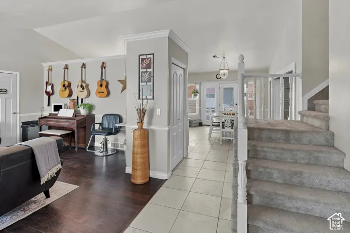 Vaulted ceiling, wood-finish flooring, staircase with carpeted treads, tiled flooring, and white interior doors