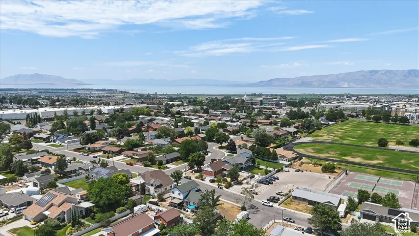 Residential neighborhood with mature trees, surrounded by distant mountains and a large body of water