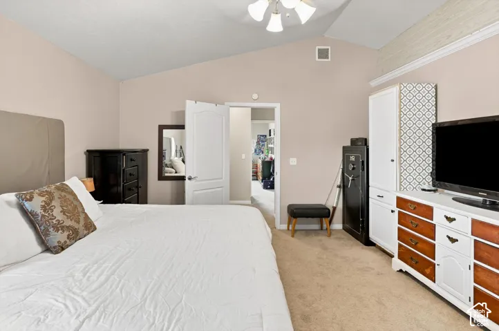 Vaulted ceiling, ceiling fan, neutral wall tones, carpeted flooring, and a white paneled door