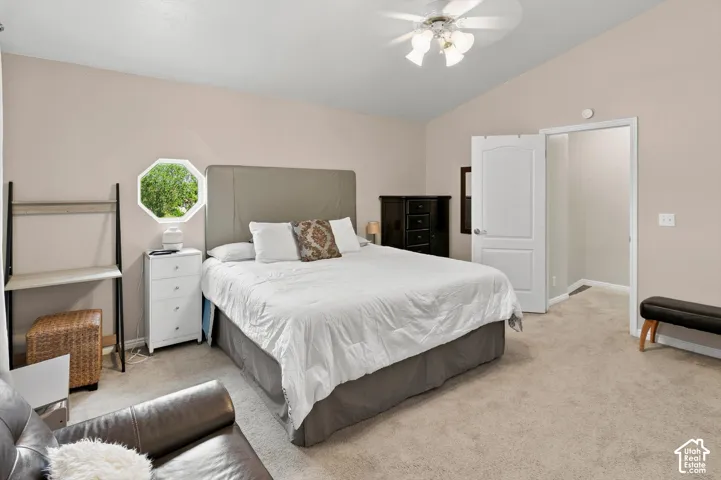 Vaulted ceiling with ceiling fan, octagonal window, and carpet flooring