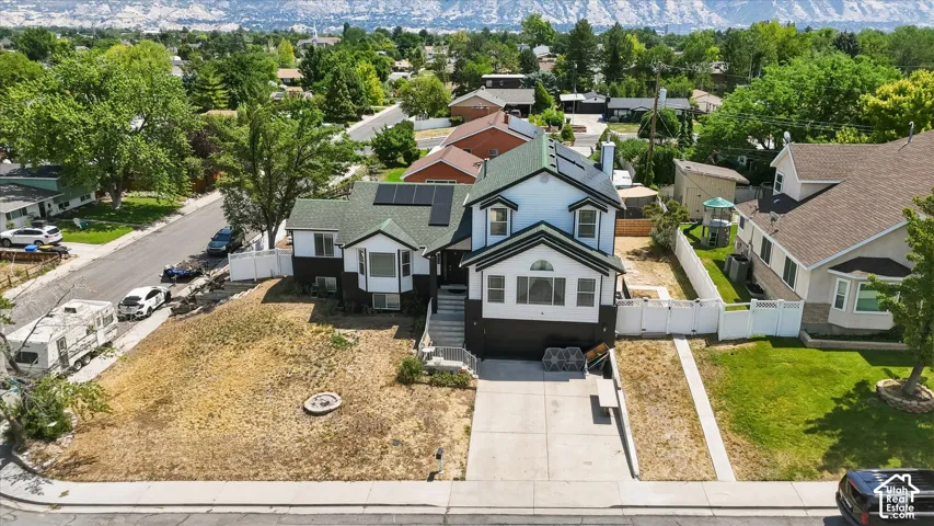 Two-story residence with a concrete driveway, a white picket fence, and a green shingle roof