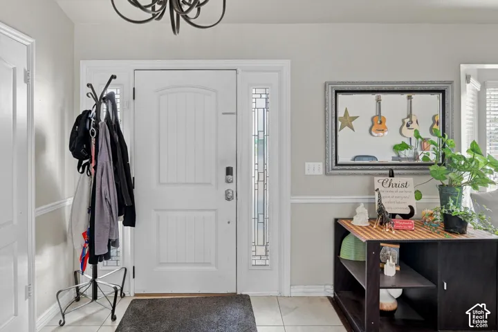 Entryway featuring a white paneled door with glass sidelight, tile flooring, and a decorative chandelier