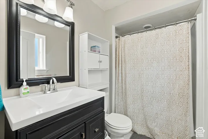 Vanity with integrated sink, black framed mirror, three-light fixture, white storage shelving, and shower area